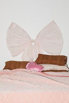 a bed with pink comforter and two pillows on top of it, in front of a white wall