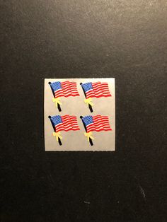 four stickers with the american flag on them are placed next to each other in front of a black surface