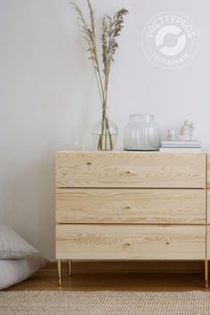 a wooden dresser sitting next to a bed in a room with white walls and wood flooring