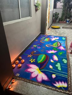 a blue rug with flowers on it in front of a door and some lit candles