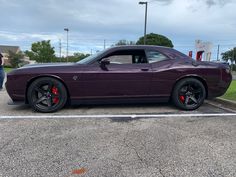 a purple car parked in a parking lot next to a person standing by it's side