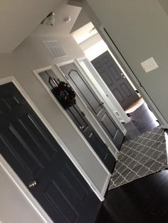 an empty room with black doors and white trim on the walls, and dark wood floors