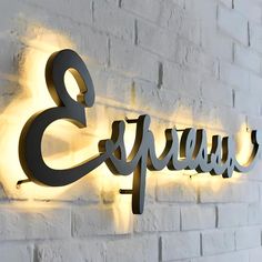 an illuminated sign on the side of a white brick wall