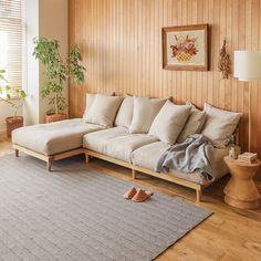 a living room with wood paneling and beige furniture in the corner, along with a rug on the floor