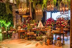 a room filled with lots of different types of flowers and plants in cages hanging from the ceiling