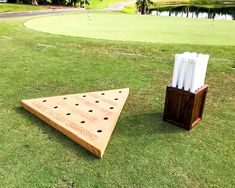 two pieces of wood sit on the grass near a golf hole with marker markers in it