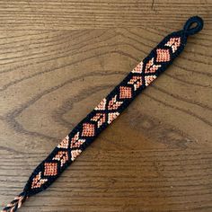 a braided bracelet with beads on top of a wooden table