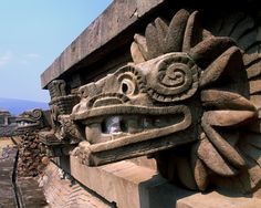 an elaborately carved stone sculpture on the side of a building in mexico with mountains in the background