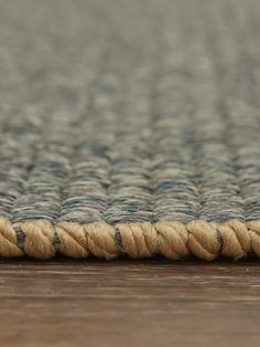 a close up view of a rug on the floor with rope and wood in the background