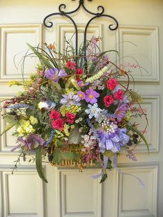 a basket filled with lots of flowers sitting on top of a door