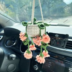 a crocheted plant hanging from the dashboard of a car with flowers on it