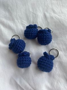 four crocheted blue apples are sitting on a white sheet and one is in the shape of an apple