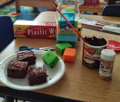 some brownies are sitting on a paper plate next to plastic containers and other items