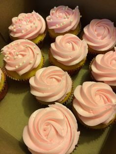 cupcakes with pink frosting and sprinkles are in a box