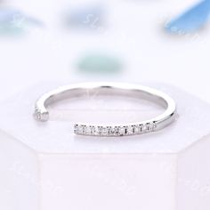 a white gold ring with five diamonds on it, sitting on top of a box