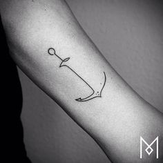 a black and white photo of a person's arm with an anchor tattoo on it