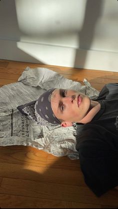 a young man sitting on top of a piece of paper wrapped in plastic wrap and looking at the camera