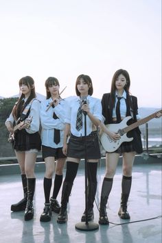 four girls in school uniforms are holding guitars and singing into microphones while standing next to each other