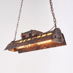 an industrial light fixture hanging from chains on a white wall in the shape of a ship