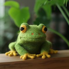 a green frog sitting on top of a wooden table