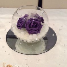 there is a glass bowl with flowers in it on top of a white table cloth