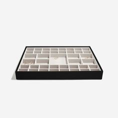 a black and white box with compartments for jewelry on it's side, against a white background