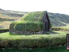 an old house with grass growing on it's roof in the middle of nowhere