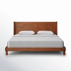 a bed with white pillows and wooden headboard