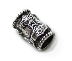 a silver beaded ring with skulls and flowers on the front, sitting on a white surface