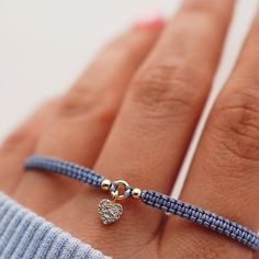 a woman's hand wearing a bracelet with a heart charm