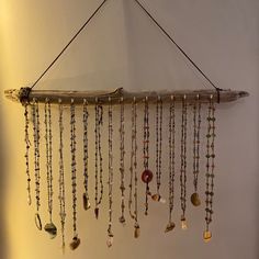 a wall hanging made out of driftwood with various beads and chains attached to it