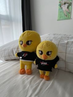 two yellow stuffed animals standing on top of a bed