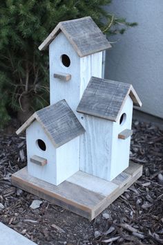 two bird houses sitting on top of a wooden stand