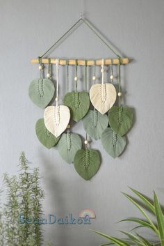 a green and white wall hanging with heart shaped leaves attached to it's sides