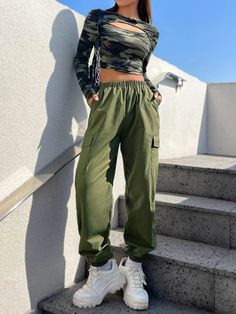 Step up your fashion game with this Camo Print Crop Tee and Cargo Pants set. The edgy camo print adds a rebellious flair, while the cut-out and patched details create a unique and eye-catching look. These pieces are made from a blend of knitted and woven fabric and offer comfort and style. Complete with long sleeves and multiple pockets, this regular-fit outfit is perfect for the fashion-forward individual. Details: Details: Cut Out, Patched, Pocket Neckline: Round Neck Pants Material: Woven Fab Camo Crop Top Outfit, Spring Combat Cotton Pants, Spring Cotton Combat Cargo Pants, Spring Combat Cotton Cargo Pants, Green Cargo Pants For Spring Streetwear, Green High Waist Cargo Pants For Streetwear, Spring Camouflage Pants For Streetwear, Trendy Camouflage Streetwear Pants, Spring Combat Cargo Pants For Streetwear