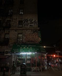 a building with graffiti on the side of it and people walking around outside at night