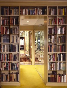 a large book shelf filled with lots of books next to a doorway that leads into a hallway