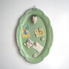 a green tray with various items on it and a heart hanging from the wall next to it