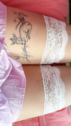 two women with tattoos on their arms and legs, both wearing lacy garters