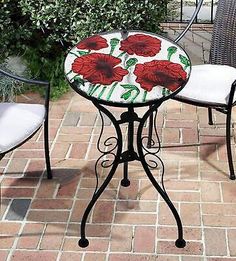 an outdoor table and chairs with flowers painted on the top, sitting on a brick patio