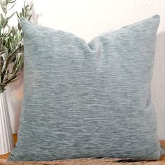 a blue pillow sitting on top of a wooden table next to a potted plant