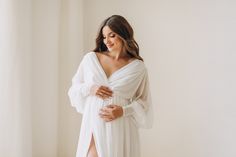 a pregnant woman wearing a white gown and holding her belly