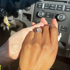 a man and woman holding hands in front of a car steering wheel with the dashboard light on