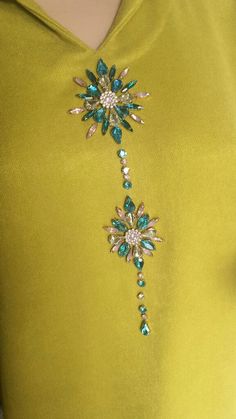 a woman wearing a yellow dress with blue and green jewels on it's neck