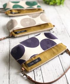 three purses sitting on top of a white wooden table next to eachother