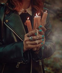 a woman holding three candles in her hands