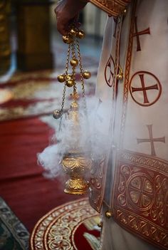 the priest is holding two bells in one hand and wearing a chain around his neck