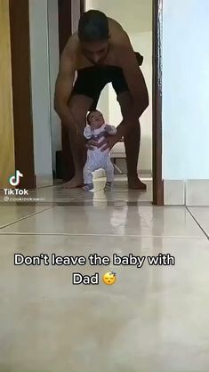 a man kneeling down next to a baby in a room with tile floors and walls