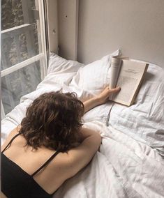 a woman laying in bed reading a book