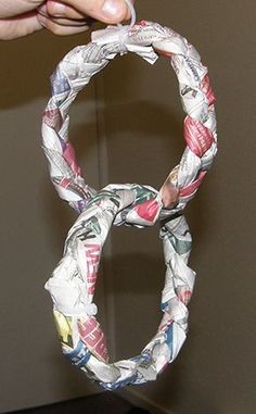 a person holding up a piece of paper in the shape of an olympic ring with newspaper pages all over it